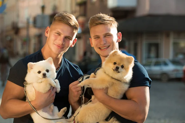 K sobě patří. Šťastná rodina na procházce. Dvojčata muži drží Chovné psy. Muži s psí mazlíčky. Happy twins s svalnatý vzhled. Spitz psi milují společnost své rodiny — Stock fotografie