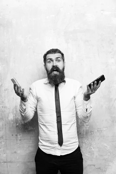 Homme d'affaires ou barbu comparer téléphone portable et smartphone — Photo