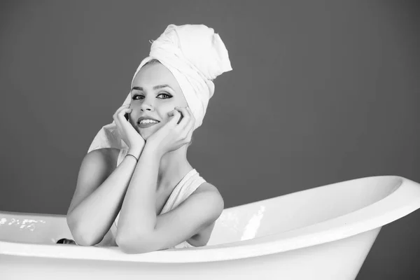 Mulher com turbante de toalha sentado na banheira branca — Fotografia de Stock