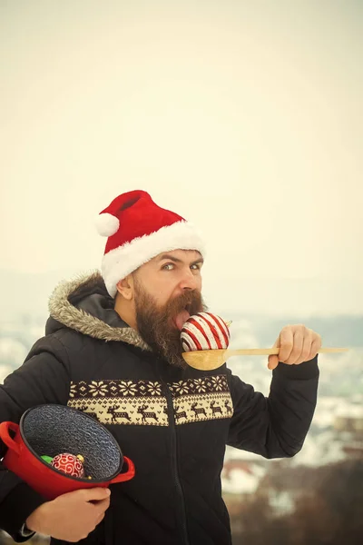Weihnachtsmann isst Weihnachtskugeln in verschneiter Landschaft — Stockfoto