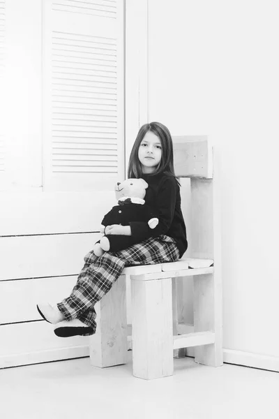 Menina bonita com bonitinho ursinho brinquedo sentado na cadeira — Fotografia de Stock
