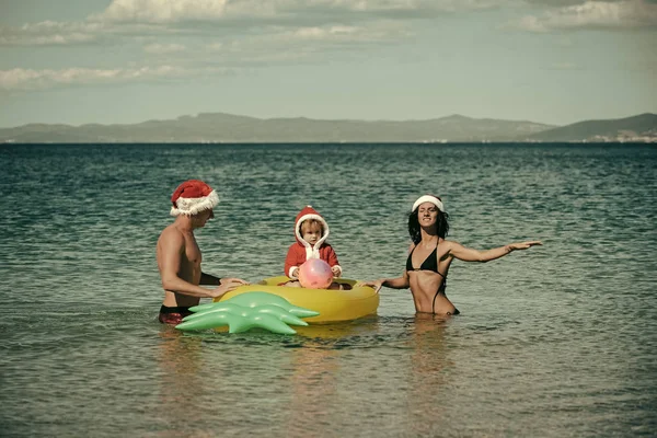 Weihnachtsglückliche Familie auf Ananas-Matratze im Wasser. — Stockfoto