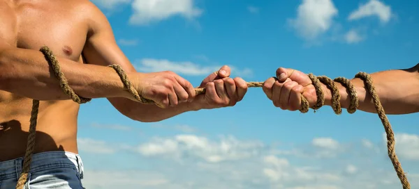 Pulling hard. Tug war is a sport. Male hands pull opposite ends of rope. Test of muscular strength. Opposite teams. Athletic contest. Sport competition. Physical strength and muscular power — Stock Photo, Image