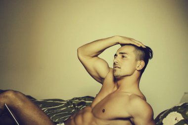 Dizüstü bilgisayar ile yatakta seksi adam