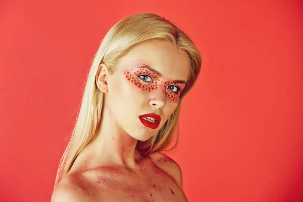 Hübsche blonde Frau mit kreativem modischem Make-up auf rotem Hintergrund — Stockfoto
