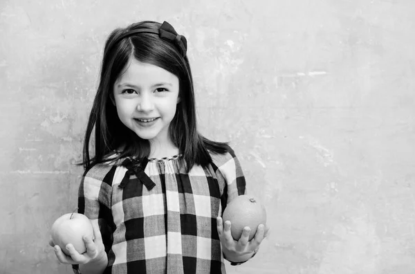 Menina feliz sorrindo com laranja e maçã nas mãos — Fotografia de Stock