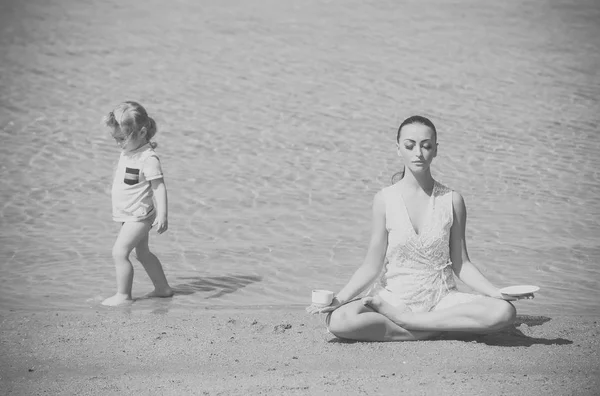 Kind en mediteren in yoga vrouw poseren met koffiekopje — Stockfoto