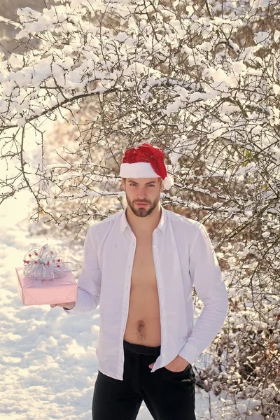 Homem em santa chapéu segurando caixa presente em madeira de neve — Fotografia de Stock