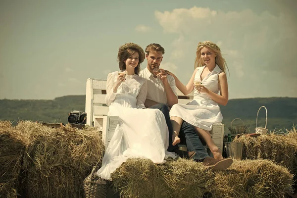 Uomo e ragazze che bevono champagne sulla panchina — Foto Stock