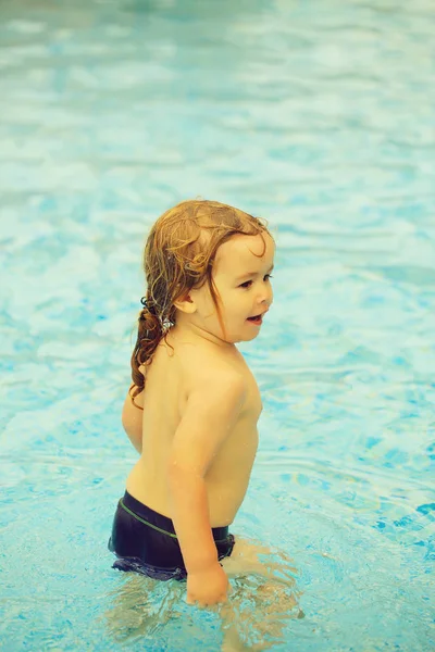 Bonito menino alegre tem banho na piscina exterior — Fotografia de Stock