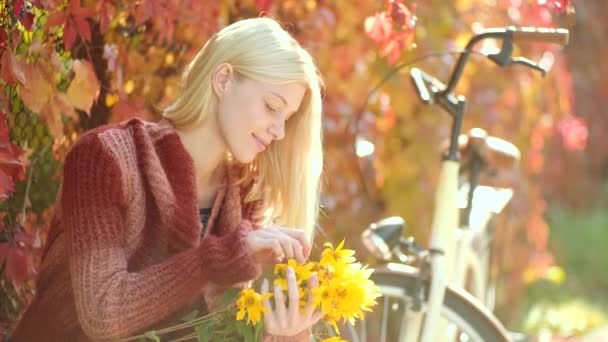 Woman with yellow flovers. Autumn happy girl and joy. Dreamy girl with long hair in knit sweater. Autumn woman with retro bike with flowers in basket in autumnal park. Clouse up portrait of girl. — Stock Video