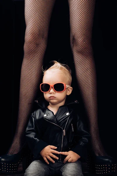 Te vamos a sacudir. Niño pequeño con gafas de sol y chaqueta rocker. Un niño pequeño con piernas femeninas. Niño estilo rock. Lindo fanático de la música. Pequeña estrella de rock. Tendencia de moda rock and roll. Música para niños —  Fotos de Stock