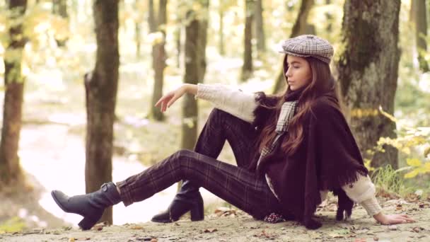 Feliz joven en el parque en el soleado día de otoño. Mujer de otoño. Hermosa joven morena sentada en un otoño caído sale en un parque . — Vídeos de Stock