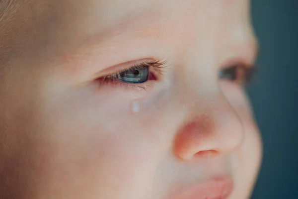 Pieni ja onneton. Pikku vauva. Vauva kyynelehtii poskeaan pitkin. Pieni poika, jolla on surulliset kasvot. Hän on itkupilli. — kuvapankkivalokuva