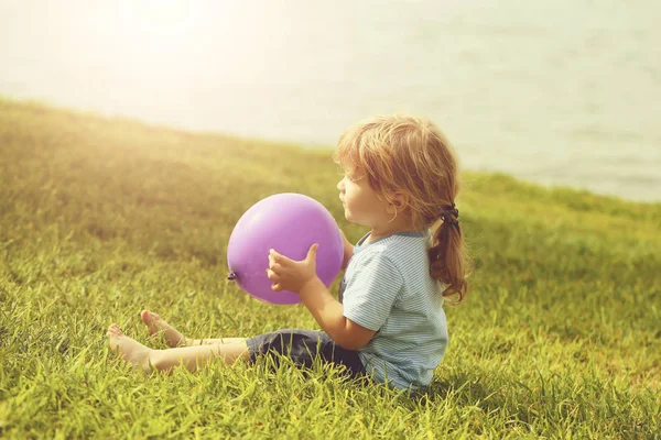Bonito menino com balão de brinquedo violeta — Fotografia de Stock