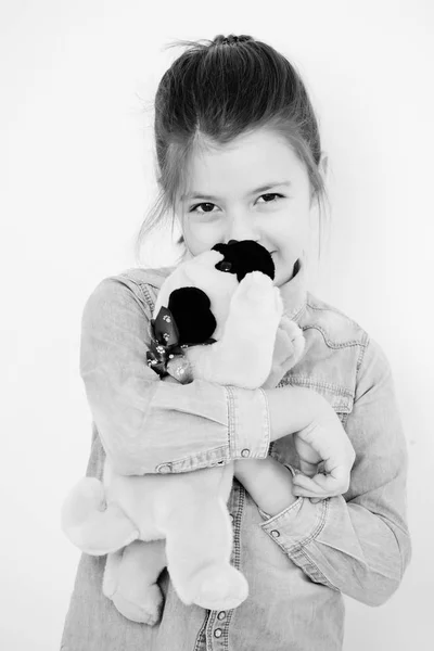 Счастливая, милая девочка обнимает игрушечную собачку — стоковое фото