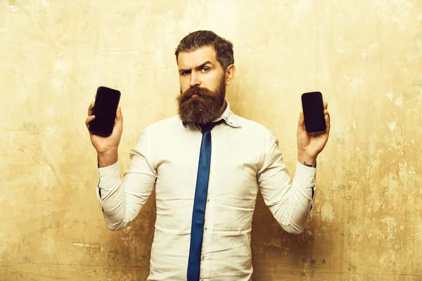 Pengusaha atau pria berjanggut membandingkan ponsel dan smartphone — Stok Foto