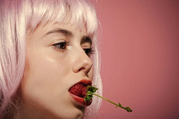 Meisje in kunstmatige haar houd rode bessen in mond. — Stockfoto