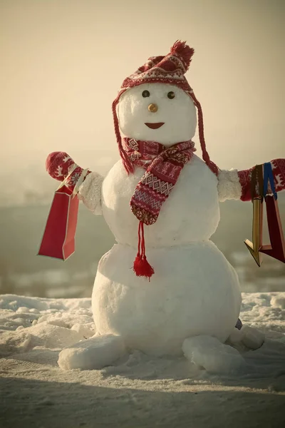 Muñeco de nieve con sombrero, mitones y bufanda con paquete de regalo . — Foto de Stock