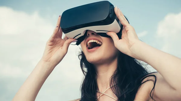 Happy girl using VR headset. The future. Woman with glasses of virtual reality. Digital future and innovation. Woman getting experience using VR-headset glasses. Visual reality concept. Future is now