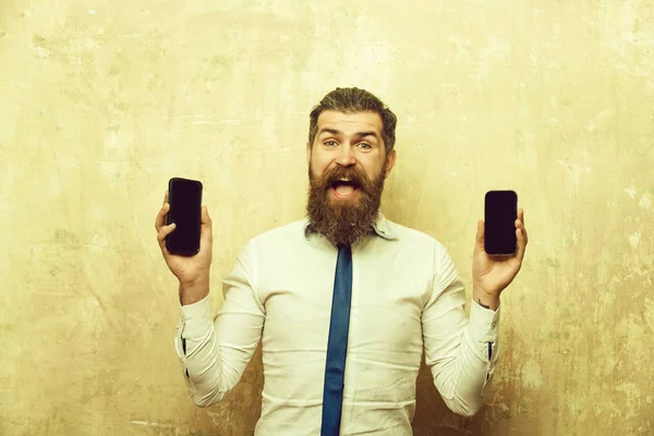 Homem barbudo ou hipster comparar telefone celular e smartphone — Fotografia de Stock