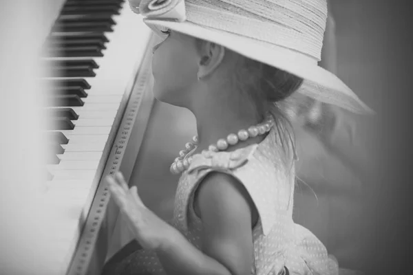 Child in vintage pink hat, dress, bead necklace at keyboard — Stock Photo, Image