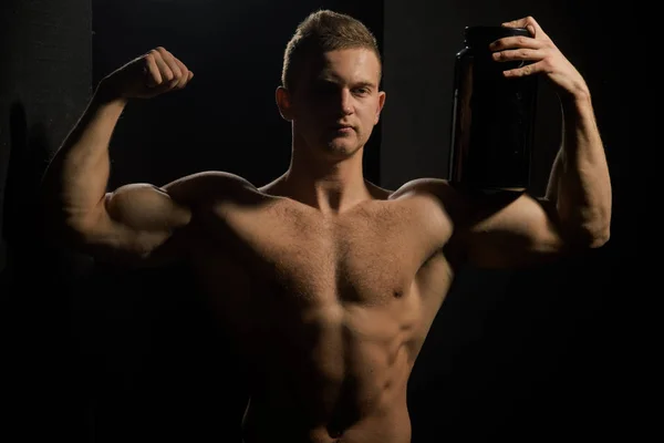 Versorgung des Körpers mit lebenswichtigen Nährstoffen. Sportlicher Mann hält Vitaminflasche in starken Armen. Männer verwenden Sport Vitaminpräparate für Muskeln. gesunde Ernährung und Fitness. Sporternährung und Vitamindiät — Stockfoto