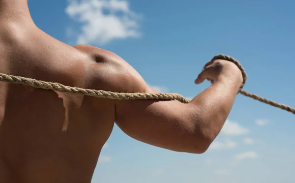 Increasing muscles power. Strong arm and shoulders tugging rope. Test of muscular strength. Sport training. Physical strength and muscular power. Sport and fitness. Male muscular hand pulling rope