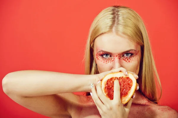 Grapefruit in handen van vrouw met creatieve modieuze make-up, vitamine — Stockfoto