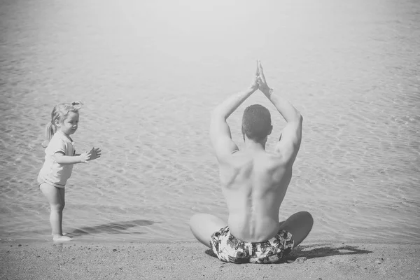 Pai e criança fazendo exercícios de ioga na praia — Fotografia de Stock