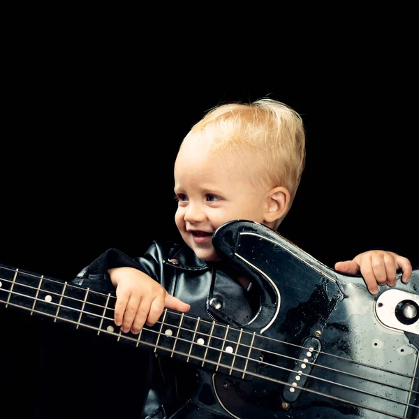 Music is fun. Small musician. Little rock star. Child boy with guitar. Little guitarist in rocker jacket. Rock style child. Rock and roll music performer. Adorable small music fan