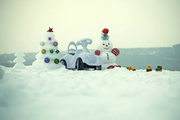 Bonhomme de neige et voiture jouet sur fond neigeux — Photo