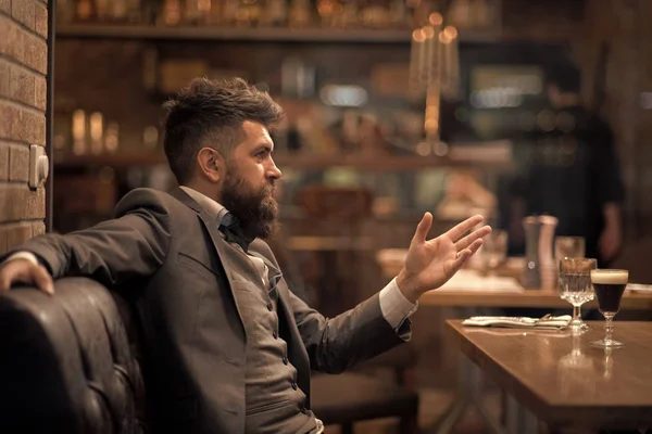 Business on go and communication. Confident bar customer speak in cafe. Businessman with long beard in cigar club. Date or business meeting of hipster in pub. Bearded man in restaurant with companion.