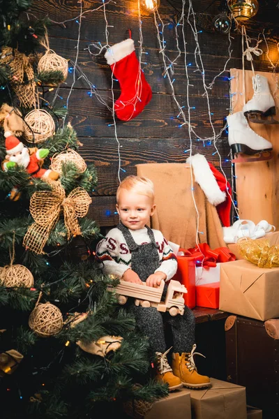 Niedliches kleines Kind öffnet Geschenk in der Nähe des Weihnachtsbaums. Frohe Weihnachten und ein gutes neues Jahr. Weihnachtstraum für Kinder. — Stockfoto