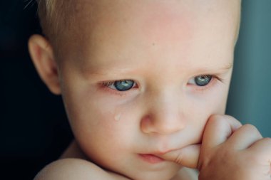 Bir sulu o. Yanağını yuvarlanan gözyaşı bebekle. Küçük bebek ağlıyor. Üzgün yüz ile küçük çocuk çocuk. Biraz sulu gözlü