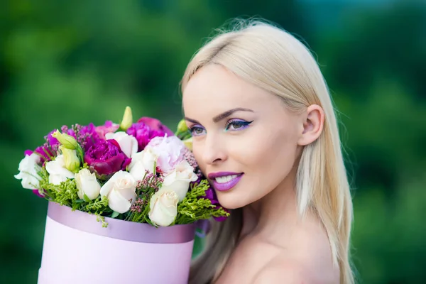 Spring woman with present flowers. Womens day. Beauty day in spring. Flowers box for woman. Valentine Beauty blonde girl. Joyful model having fun celebrating with colorful flowers.