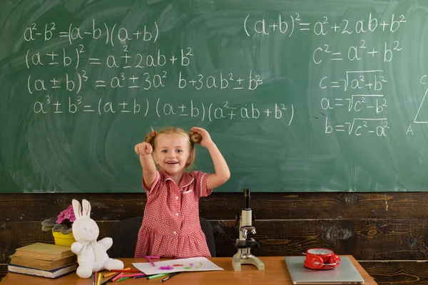 Joyeux élève pointé du doigt sur le tableau de la classe. Les élèves de l'école primaire aiment apprendre. Je te choisis. — Photo