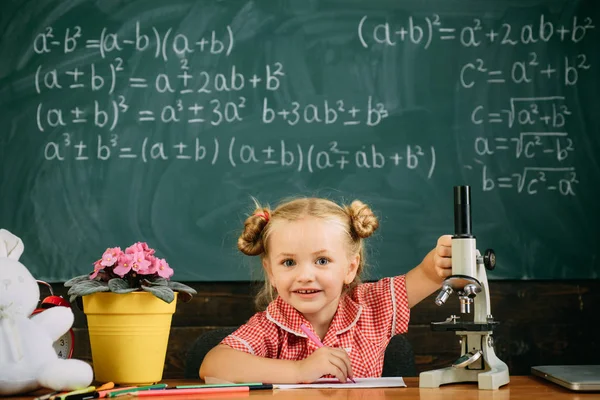 Исследования маленьких девочек с микроскопом в школьной лаборатории. Ребенок делает академическую и исследовательскую работу в классе. Try and try until you success — стоковое фото