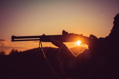 Kalibre tüfek avcılık. Tüfek Hunter içinde güzel gün batımı kontrast. Avcı silüeti. Tüfek tetiği çekti. Silahın namlu.