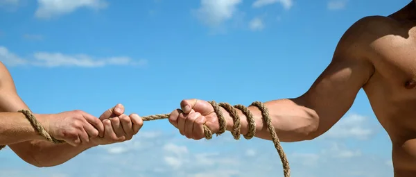 Pulling rope. Male hands pull opposite ends of rope. Tug war is a sport. Test of muscular strength. Opposite teams. Athletic contest. Sport competition. Physical strength and muscular power