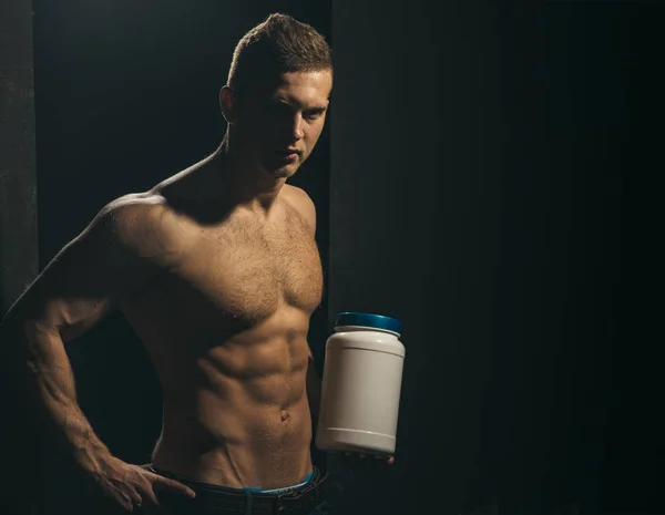 Affecting muscle growth. Man use sport vitamin supplements for muscle building. Sport nutrition and vitamin diet. Athletic man hold vitamin bottle in strong arms. Healthy diet and fitness, copy space — Stock Photo, Image