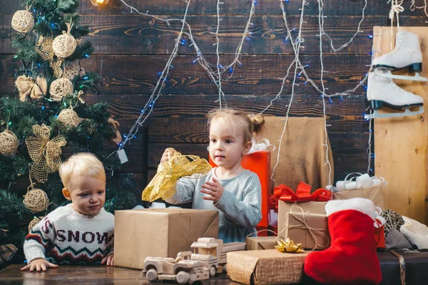 子新年。クリスマスの子供たち。ギフトで遊んでいる子供たち。大晦日。クリスマスのギフト ボックスと幸せな家族。クリスマス プレゼントを開ける子供たち。冬の夜は家で。クリスマスの幸せな笑顔の子 — ストック写真