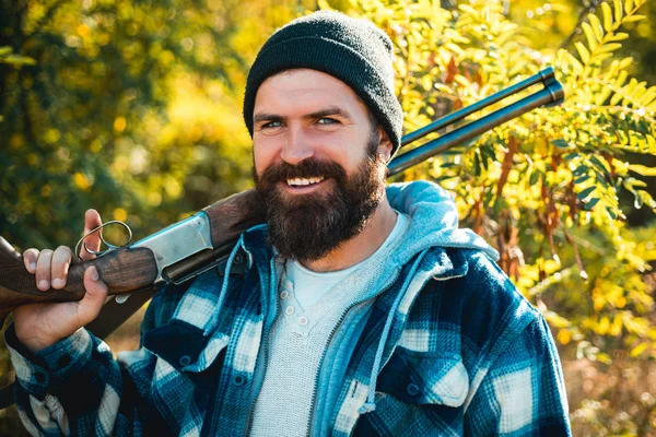 Fotos para Barbería. Hombre cazador barbudo sosteniendo arma y sonriendo. Cazador con barba larga a la caza. Barbería vintage. Ideas sobre Peluquería y Peluquería . — Foto de Stock