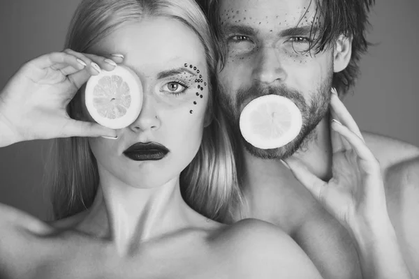 young couple of woman and man with makeup hold lemon