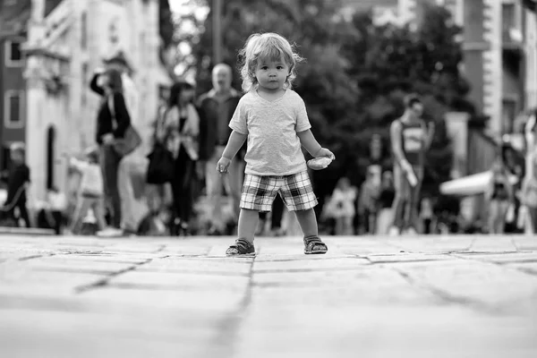 Baby boy with bun on pavement