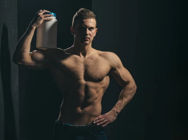 Gezondheid en fitness doelstellingen. Gezonde voeding en fitness. Atletische man houd vitamine fles in de sterke armen. Man gebruik sport vitamine supplementen voor spieropbouw. Sport-voeding en vitamine-voeding — Stockfoto