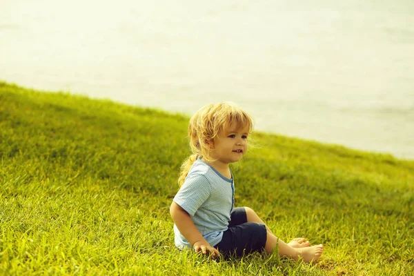 Lindo bebé niño se sienta en verde hierba — Foto de Stock