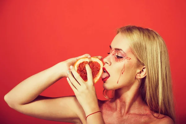 Жінка з креативним модним макіяжем тримає грейпфрут, вітамін — стокове фото