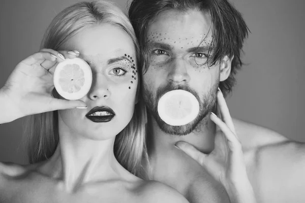 man and girl with makeup hold lemon