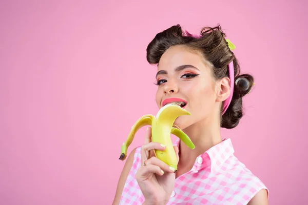 retro woman eating banana. pinup girl with fashion hair. banana dieting. pin up woman with trendy makeup. pretty girl in vintage style, copy space. Welcome to fruit paradise